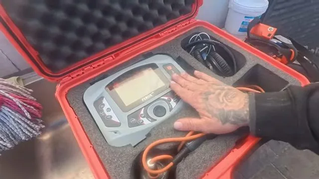 Hand resting on the screen of an acoustic leak detector sitting open in a red hard case.