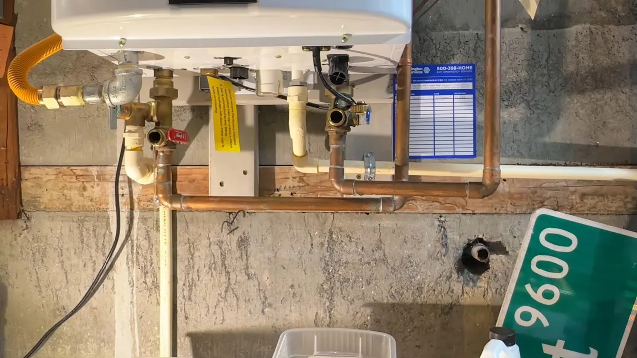 Wall-mounted tankless water heater with a yellow flexible gas line, brass valves and copper piping beneath it.