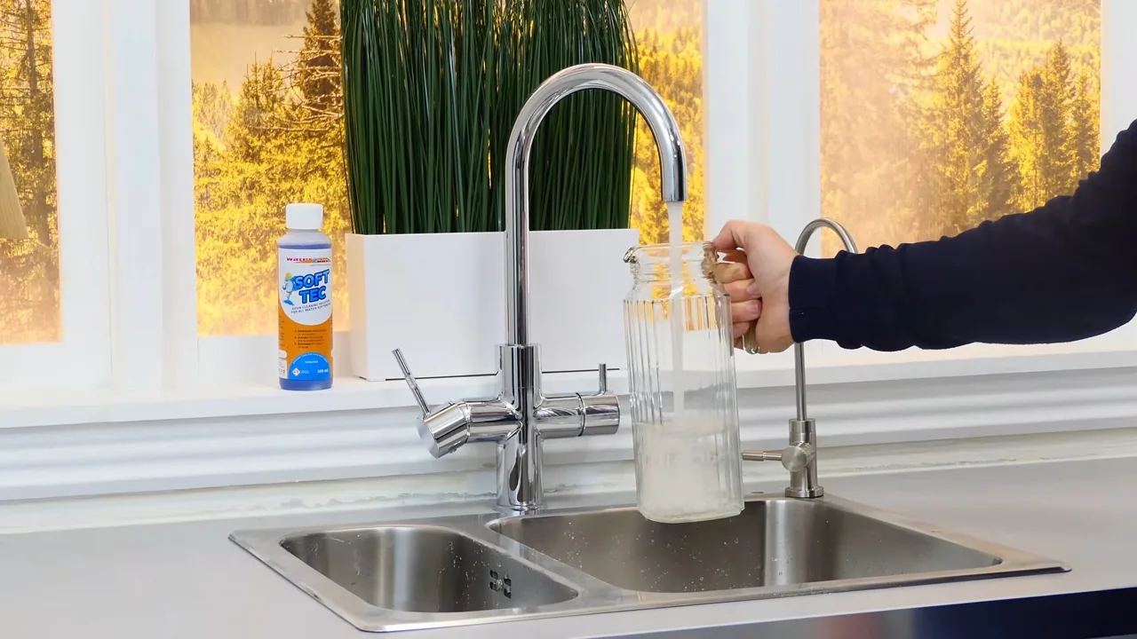 Water running from a kitchen tap into a glass pitcher, the water looking milky.